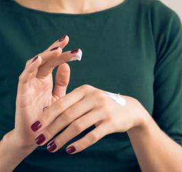 Kobieta pielęgnuje swoje dłonie, nakłada na nie krem.